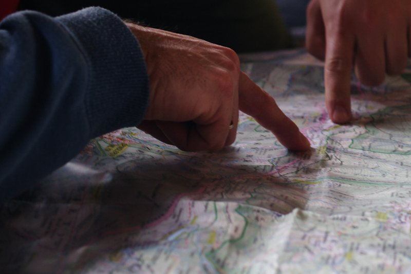 Two people pointing to places on a paper map spread across a table